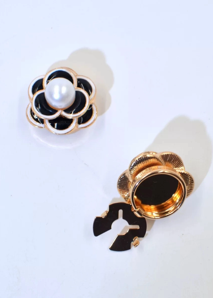 Black, white, and gold flower button cover with a pearl center on a white background