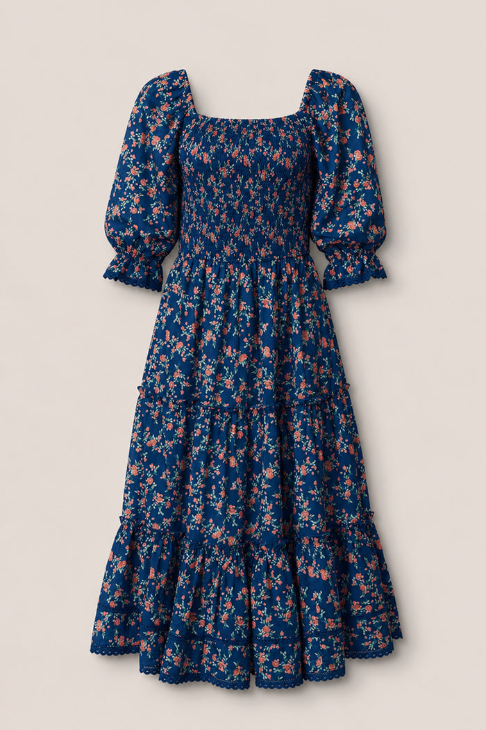 The Madeline Dress in Midnight Vibrant Chintz by Ivy City Co features a navy floral print, smocked bodice, puffed half sleeves, ruffled tiered skirt, and scalloped hem—an ankle-length maternity-friendly dress for any occasion.