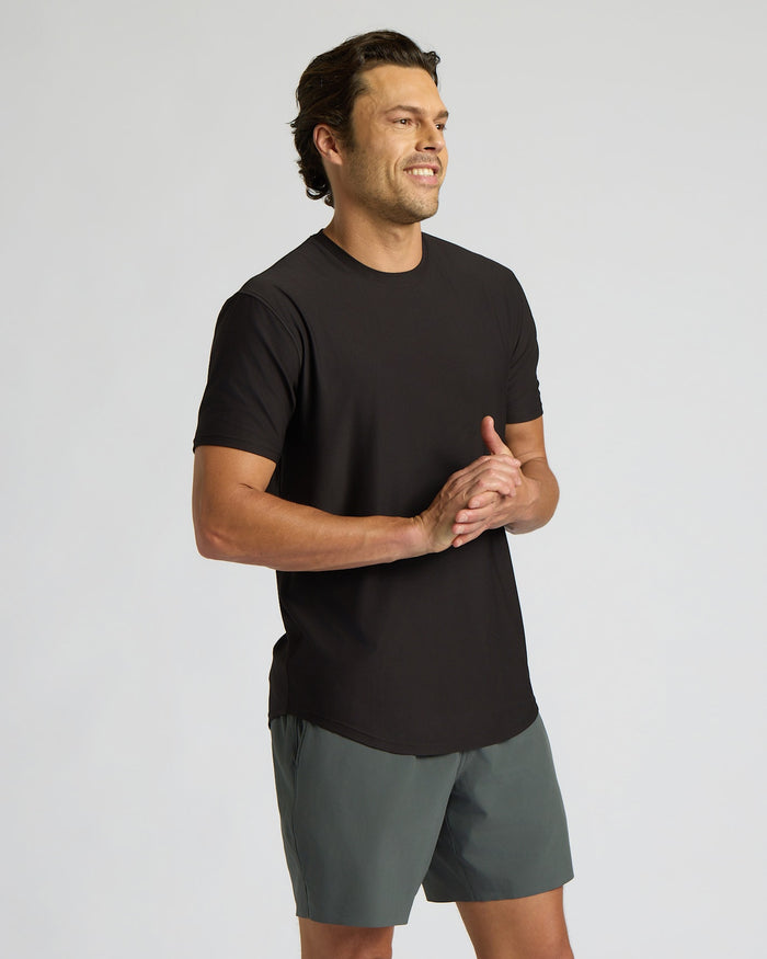 Man wearing a black t-shirt and gray shorts on a light gray background