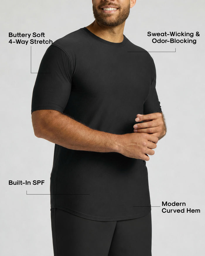 A man wearing a black short-sleeve athletic shirt with text callouts highlighting features such as buttery soft 4-way stretch, sweat-wicking and odor-blocking, built-in SPF, and modern curved hem.