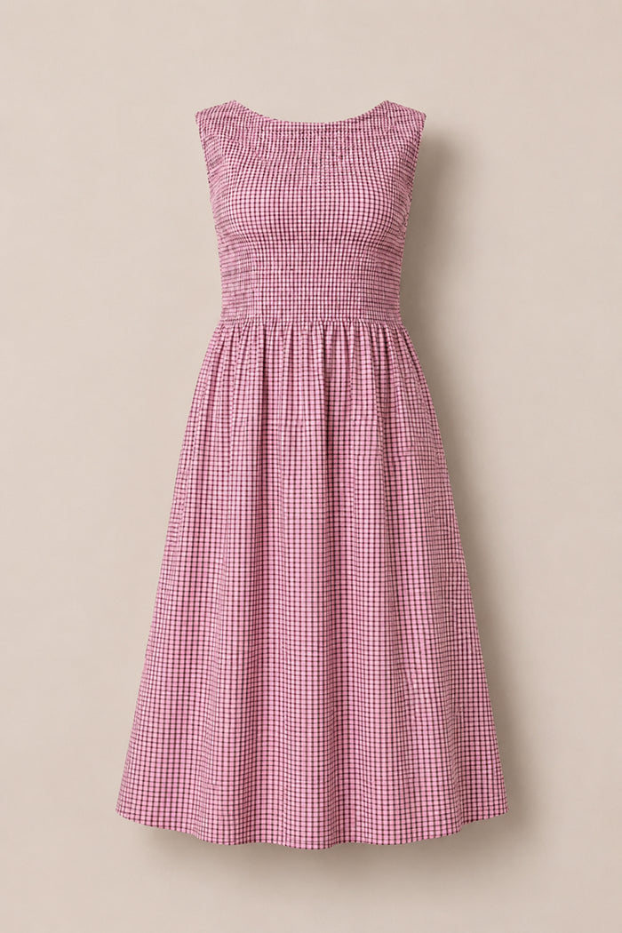 The Ana Dress in Pink & Brown Gingham by Ivy City Co is a sleeveless midi dress with a smocked, ruched bodice, flared skirt, and pink and brown gingham check pattern, shown against a plain beige background.