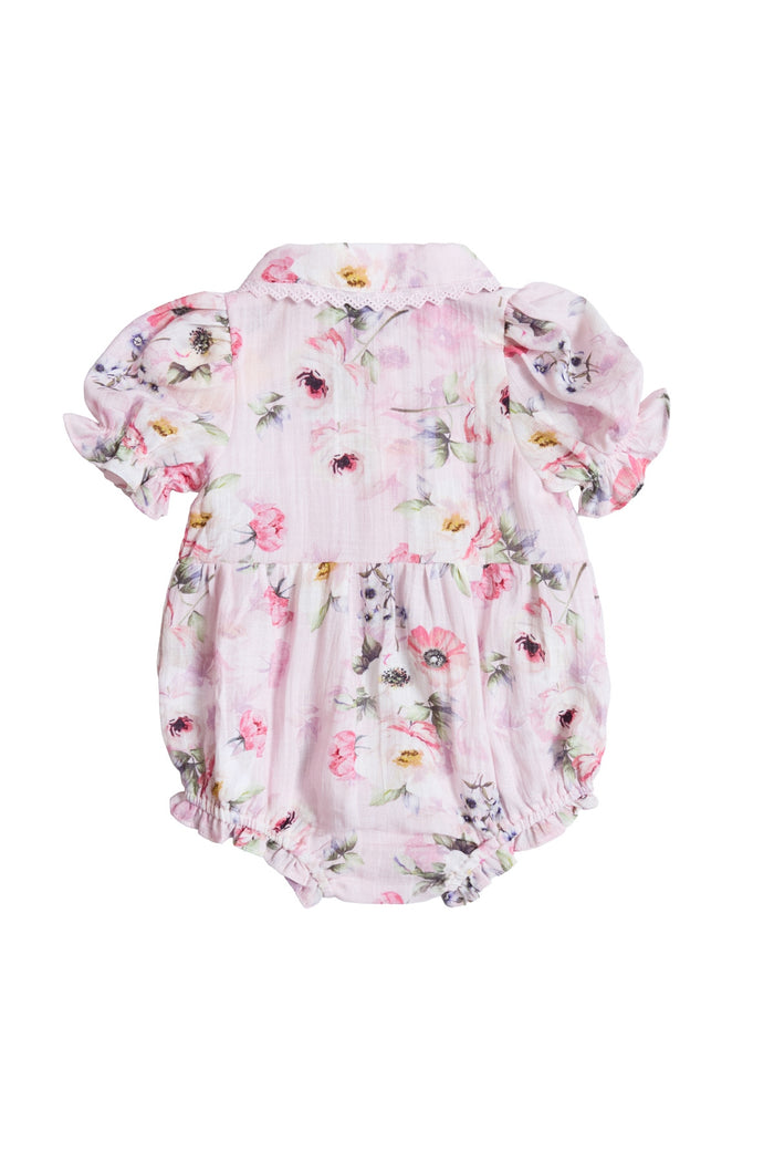 The Ivy City Co Baby Sophia Romper in Roselyn Pink has short puffed sleeves, a pink, purple, and yellow floral pattern, elastic leg openings, a small collar, and is shown from the back—ideal for mommy-and-me moments.