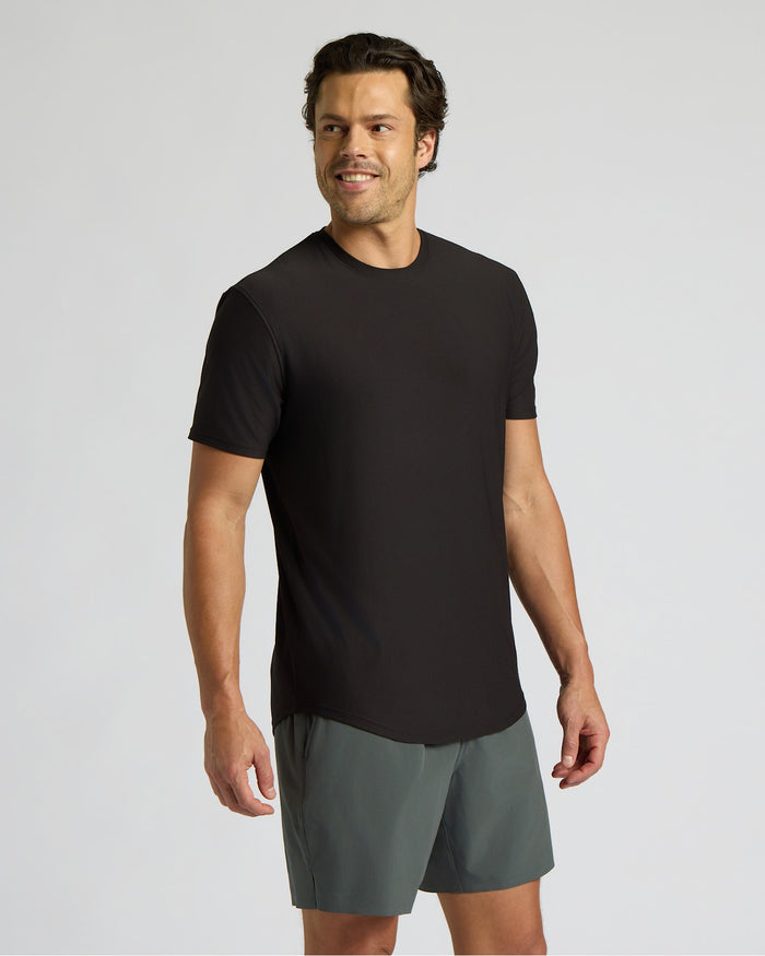 Man wearing a black t-shirt and gray shorts on a light gray background