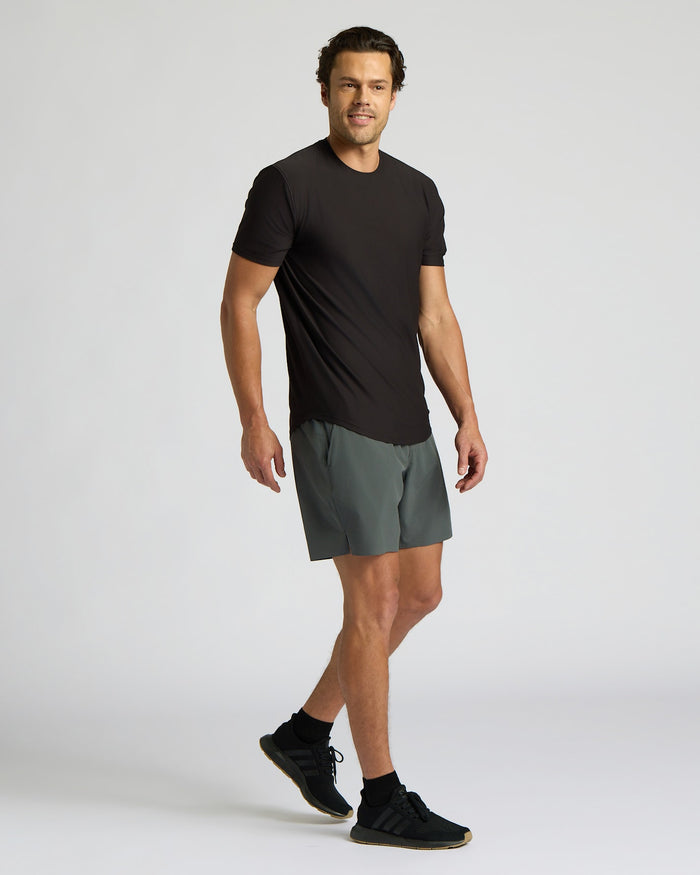 Man wearing a black t-shirt and gray shorts on a white background
