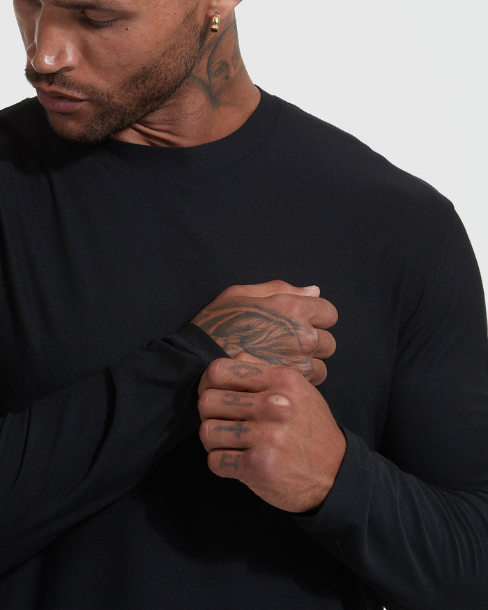 Man wearing Black Active Long Sleeve Crew Neck T-Shirt, adjusting sleeve cuff.