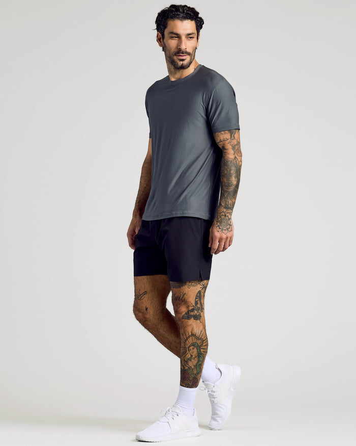 Man wearing Carbon Active Crew Neck Tee, black shorts, white socks, running shoes.