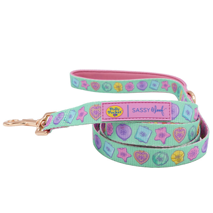 The Sassy Woof Dog Leash - Polly Pocket™ features a pastel design with a neoprene handle, pink lining, colorful Polly Pocket™ charms, gold hardware, and tags reading "Polly Pocket" and "Sassy Woof.