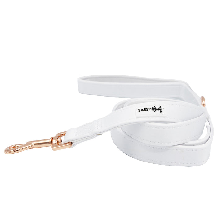 The Sassy Woof Dog Leash - Pup of Honor features white satin, rose gold hardware, a Sassy Woof logo tag, and a soft neoprene handle for comfort. Coiled neatly with the handle on top, it's perfect to pair with your pup's matching accessories.