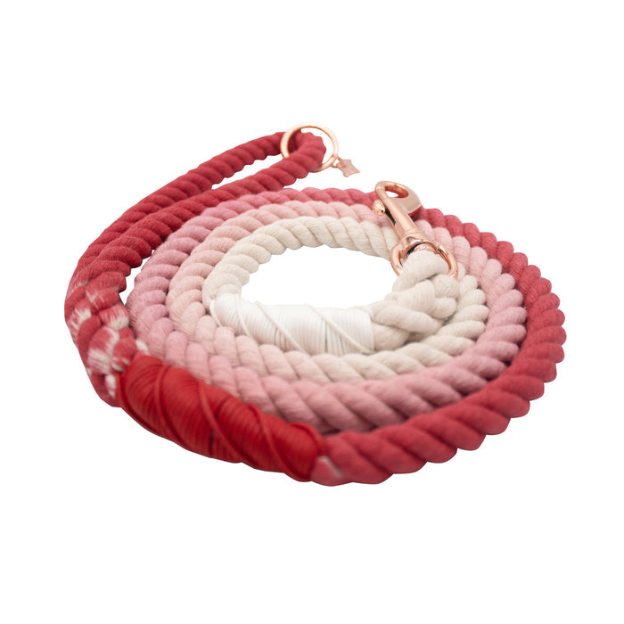 The Sassy Woof Dog Rope Leash - Poppy is a hand-crafted cotton leash with an ombre gradient from deep red to light pink and white, finished with a rose gold clasp, shown on a white background.