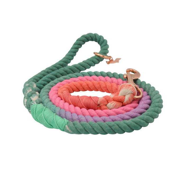 The Sassy Woof Dog Rope Leash - Unicorn is a hand-crafted, multicolored ombre leash in green, pink, purple, and coral with a rose gold clasp, shown coiled on a white background.