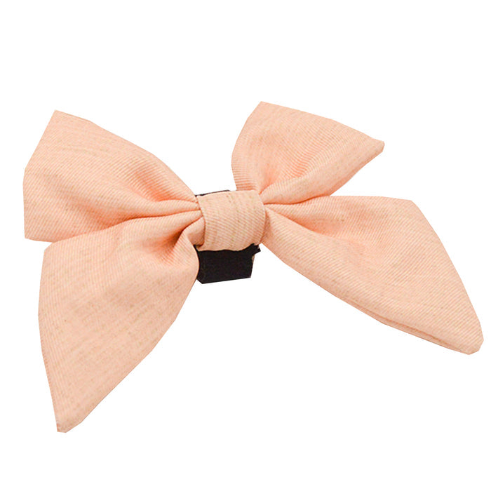 The Sassy Woof Dog Sailor Bow - Pinot is a light peach bow with wide loops and tails, attached to a black hair clip and displayed on a white background.