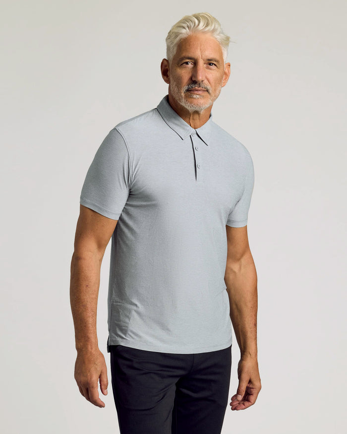 Man wearing Heather Light Gray Active Polo with dark trousers.