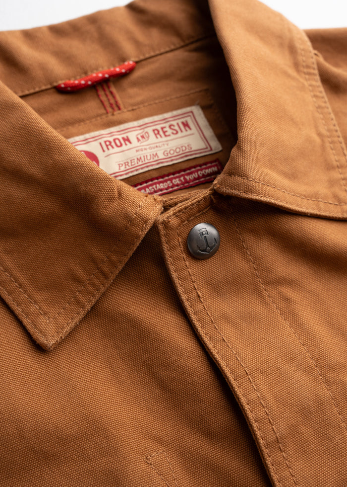 Close-up of a brown Iron and Resin jacket collar with a visible label and button, showcasing premium craftsmanship and style.