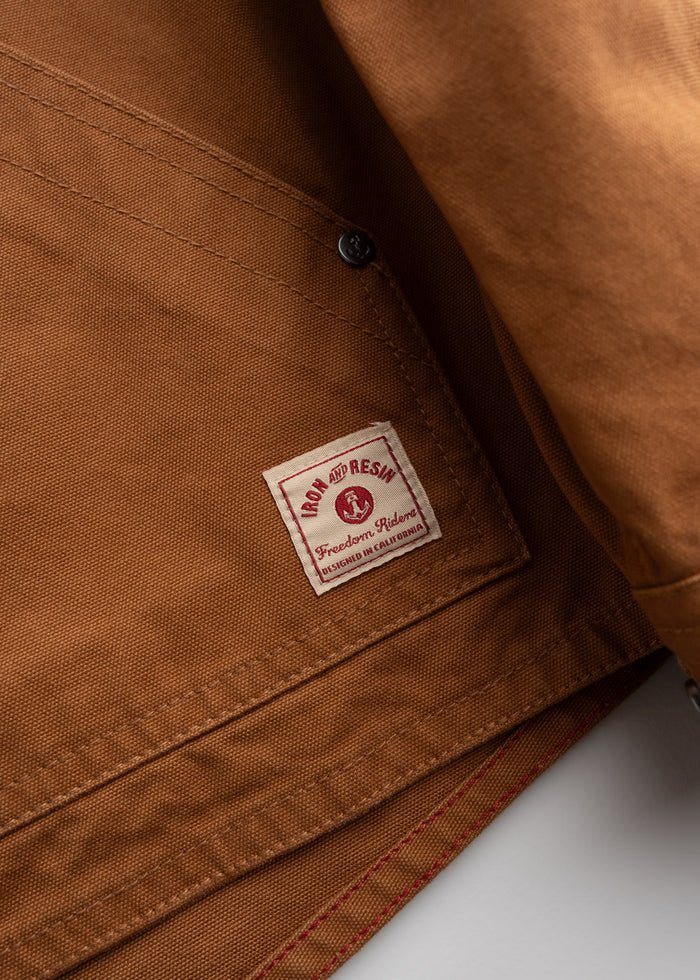 Close-up of a brown jacket with a label reading "Iron and Resin, Freedom Riders, Designed in California" on the inside.