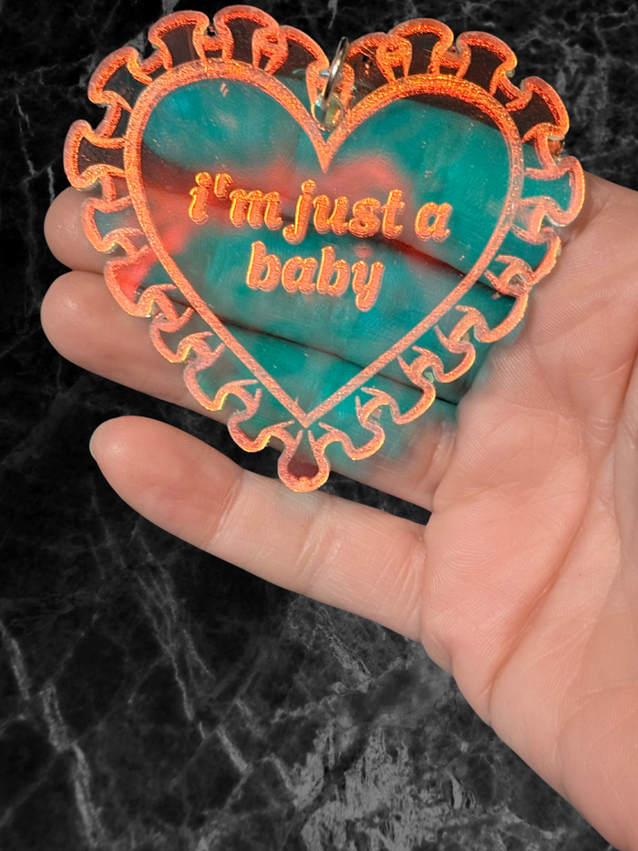 Iridescent heart acrylic keychain with "Just a Baby" inscription from Adorrible, featuring a shiny, colorful design and silver keyring.