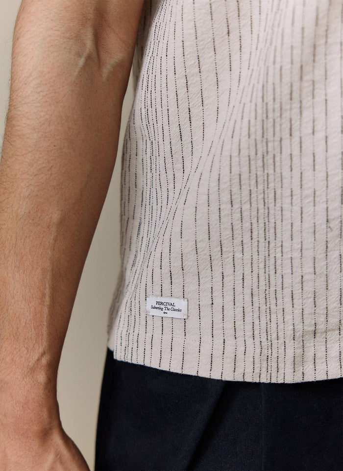 Close-up of the textured ecru cotton with vertical stitching and branded label on the Percival Leland Cuban Shirt.