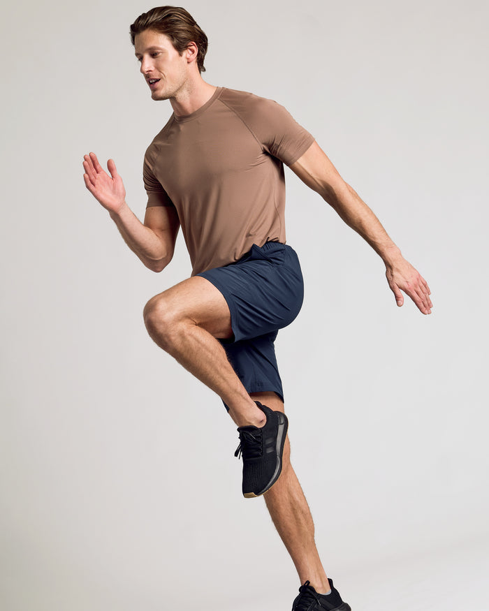 Man wearing Navy 9 Active Quick Dry Shorts, performing a high-knee drill.