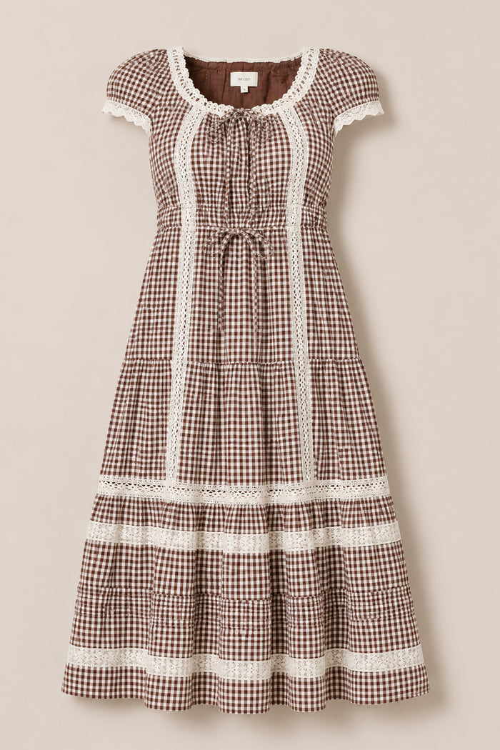 The Palermo Dress in Hickory Gingham by Ivy City Co features a brown and white gingham pattern with short puff sleeves, lace trim, a gathered waist, and a tiered skirt. Displayed on a neutral background, this maternity-friendly dress ensures comfortable style at every stage.