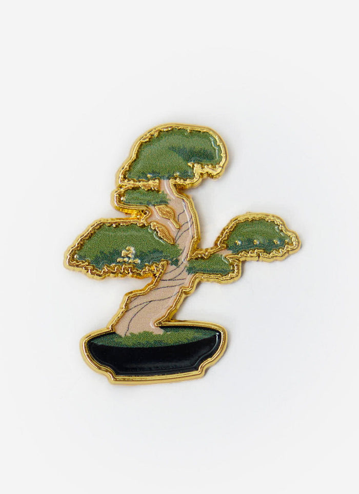 A close-up of the Percival Bonsai Pin Badge, a collectable metal pin with a gold outline and green enamel detail.
