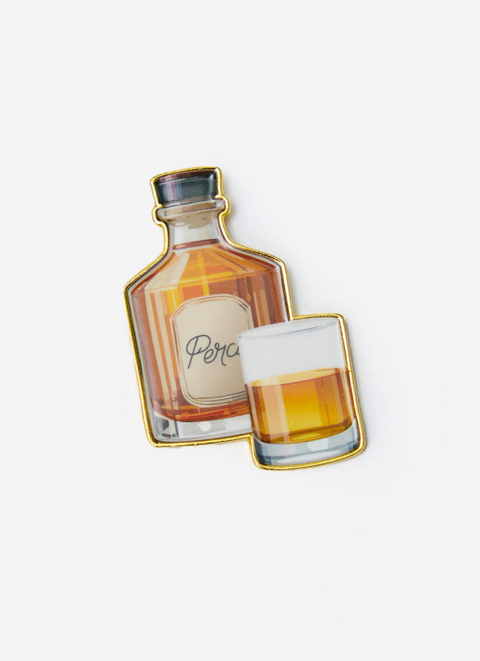 The Percival Old Fashioned metal pin badge, featuring an illustration of a bourbon bottle and glass, on a white background.