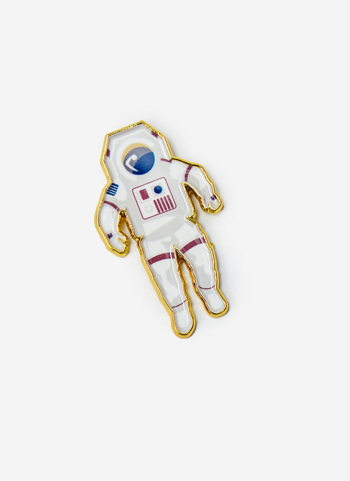 The Percival Spaceman Pin Badge, a white and gold astronaut-shaped metal accessory, on a plain white background.