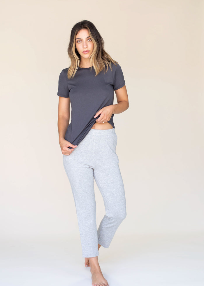 Woman wearing a dark gray t-shirt and light gray leggings on a beige background