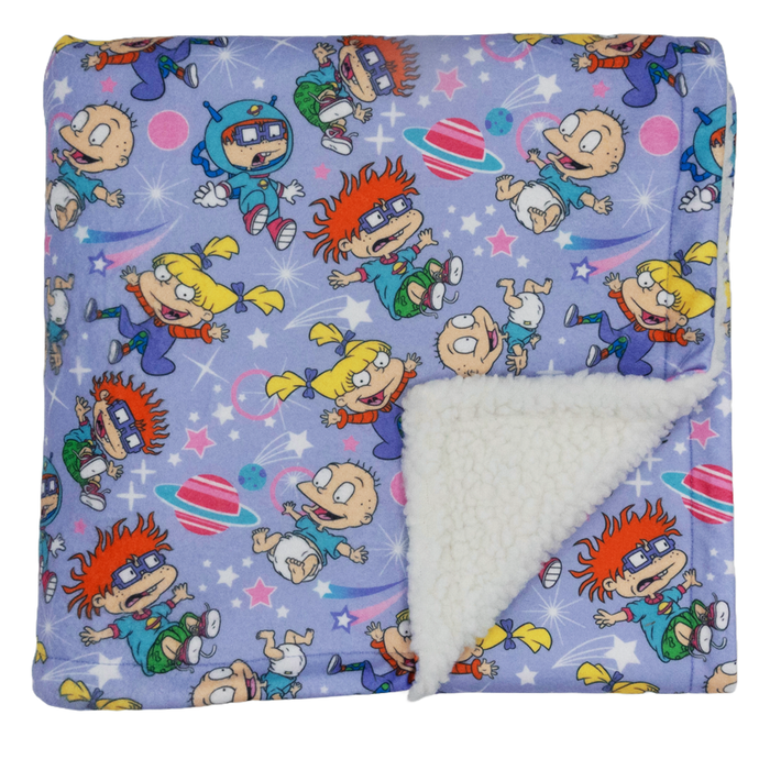 The Sassy Woof Pet Blanket - Nickelodeon Rugrats™ features a soft purple design with Tommy, Chuckie, and Angelica, plus a cozy white sherpa lining visible on one corner—perfect for your dog’s comfort.