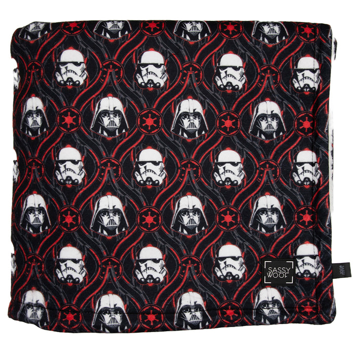 Cuddle up with the Sassy Woof Pet Blanket - STAR WARS™ The Dark Side, featuring Darth Vader and Stormtrooper helmets in red circles on a soft black sherpa top, finished with a black Sassy Woof label in the corner.