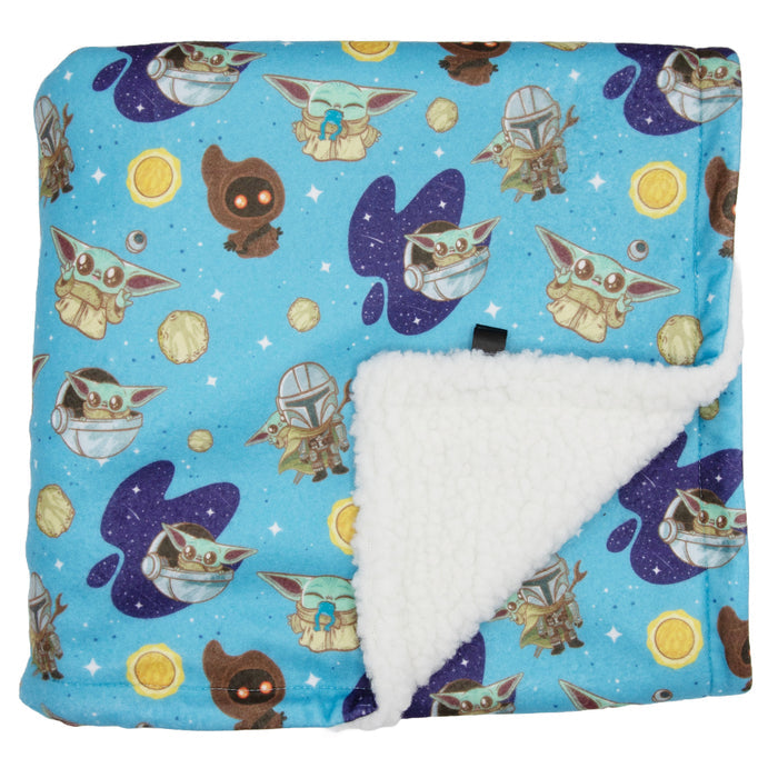 The Sassy Woof Pet Blanket – STAR WARS™ The Mandalorian™ is made from 100% polyester with a soft microfiber top, featuring Grogu, the Mandalorian, Jawas, and planets on a starry background and cozy white sherpa lining.