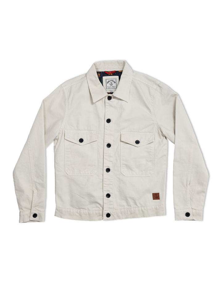 Cream jacket with black buttons, two chest pockets, and a visible inner label. Simple, stylish design on a white background.