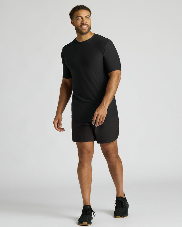 Man wearing a black t-shirt and shorts on a white background