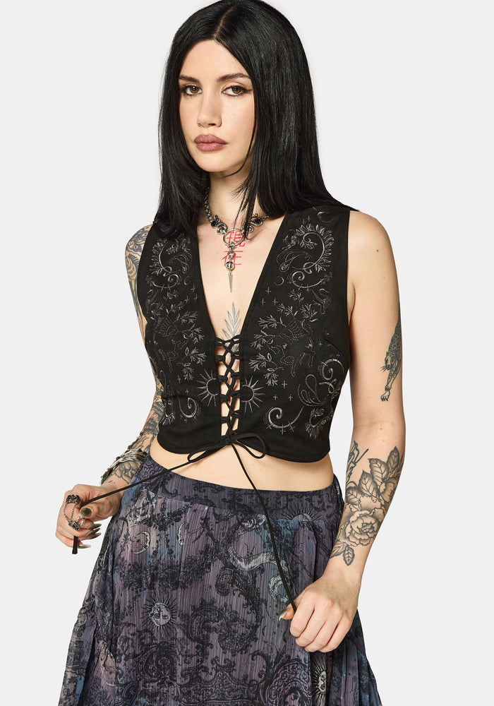 Woman wearing a black lace-up top with floral patterns on a white background