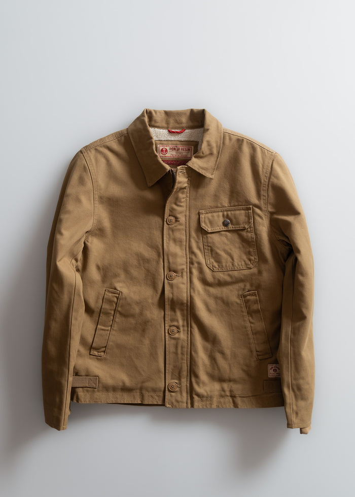 Brown canvas jacket with button closure, chest pocket, and side pockets, displayed against a plain white background.