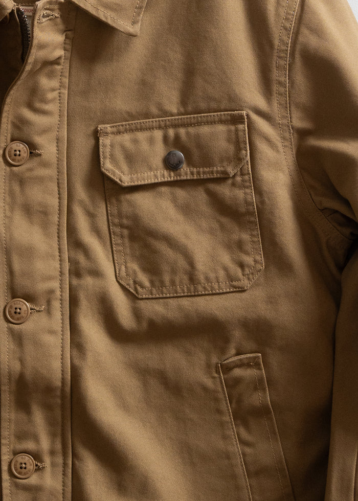 Close-up of a brown jacket with buttons and a chest pocket, showcasing its rugged texture and casual style.