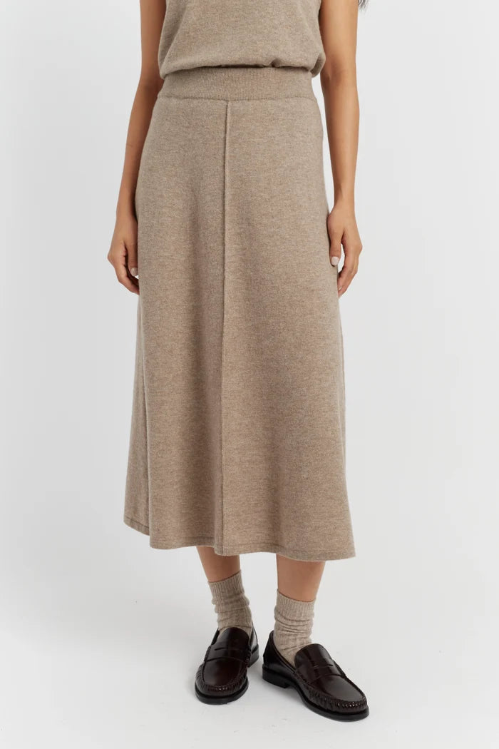 Person wearing a beige knit skirt on a white background