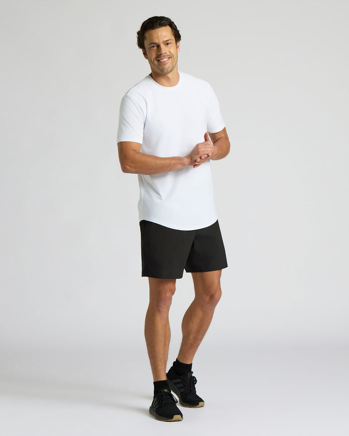 Man wearing a white t-shirt and black shorts on a light gray background
