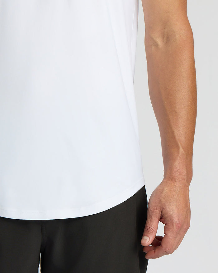 Person wearing a white shirt and black pants against a plain background