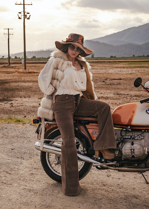 Woman in vintage attire sitting on a motorcycle in a desert landscape wearing Soul Sister since 1969