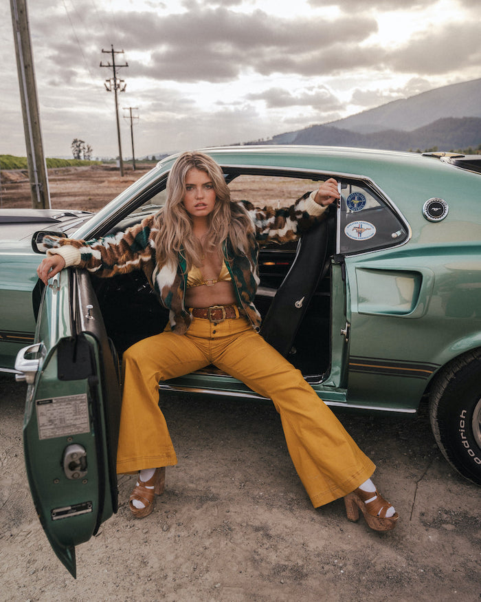 Woman sitting in the driver's seat of a vintage car with mountains in the background wearing Soul Sister since 1969